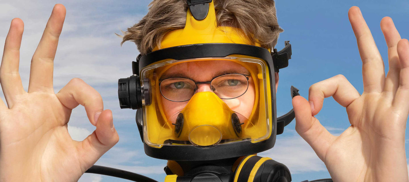 Person wearing a yellow diving helmet with a maskoptic glasses against a blue sky.