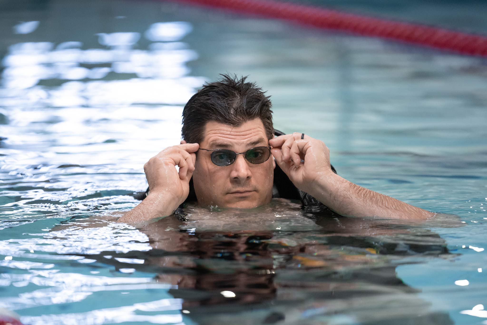 Man adjusting prescription glasses in a pool