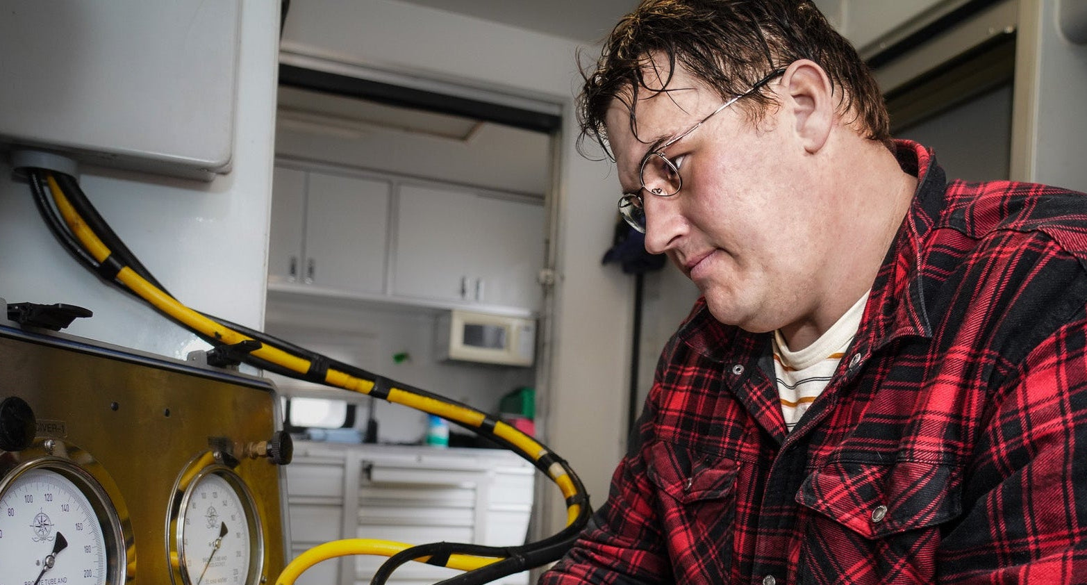 Person working with equipment involving gauges and hoses in a kitchen setting