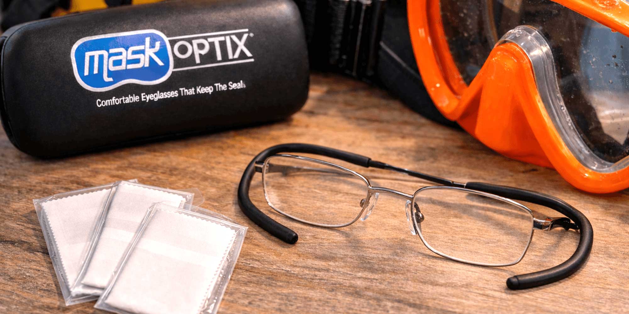 Mask Optix eyeglasses with protective case and cleaning cloths on a wooden surface