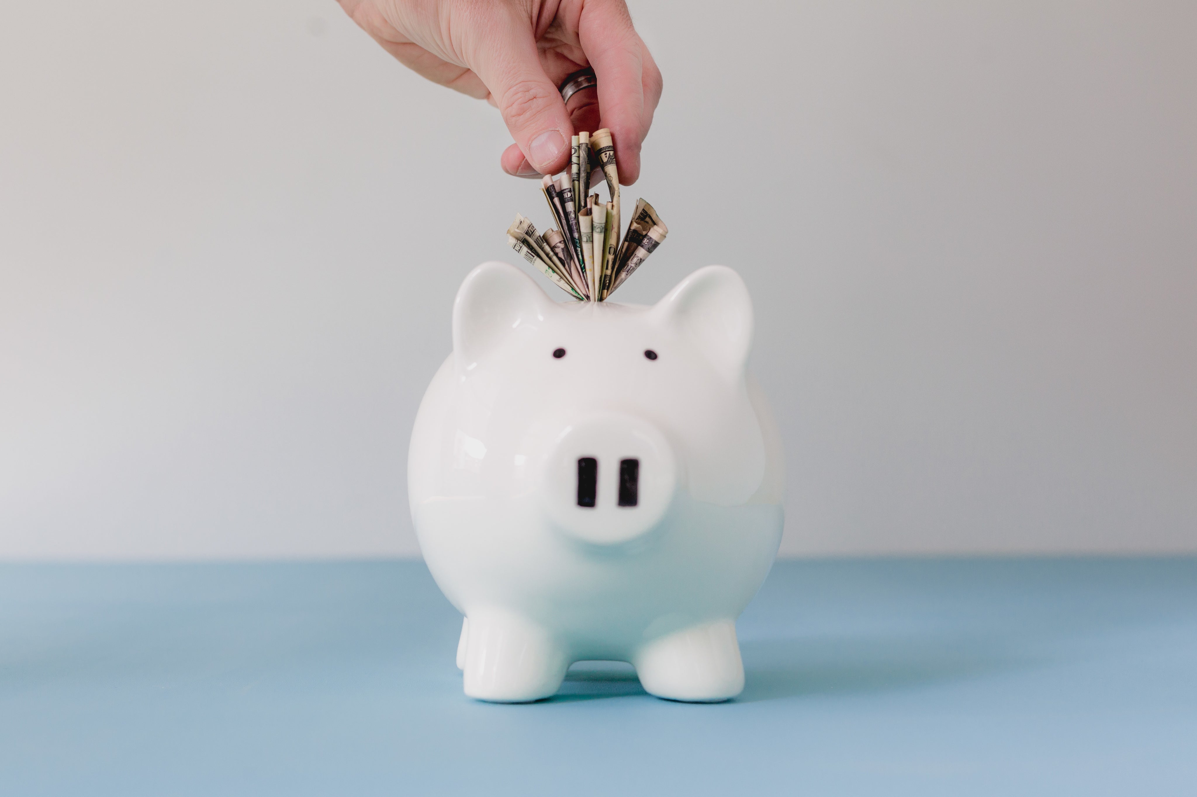 Hand placing money in a piggy bank